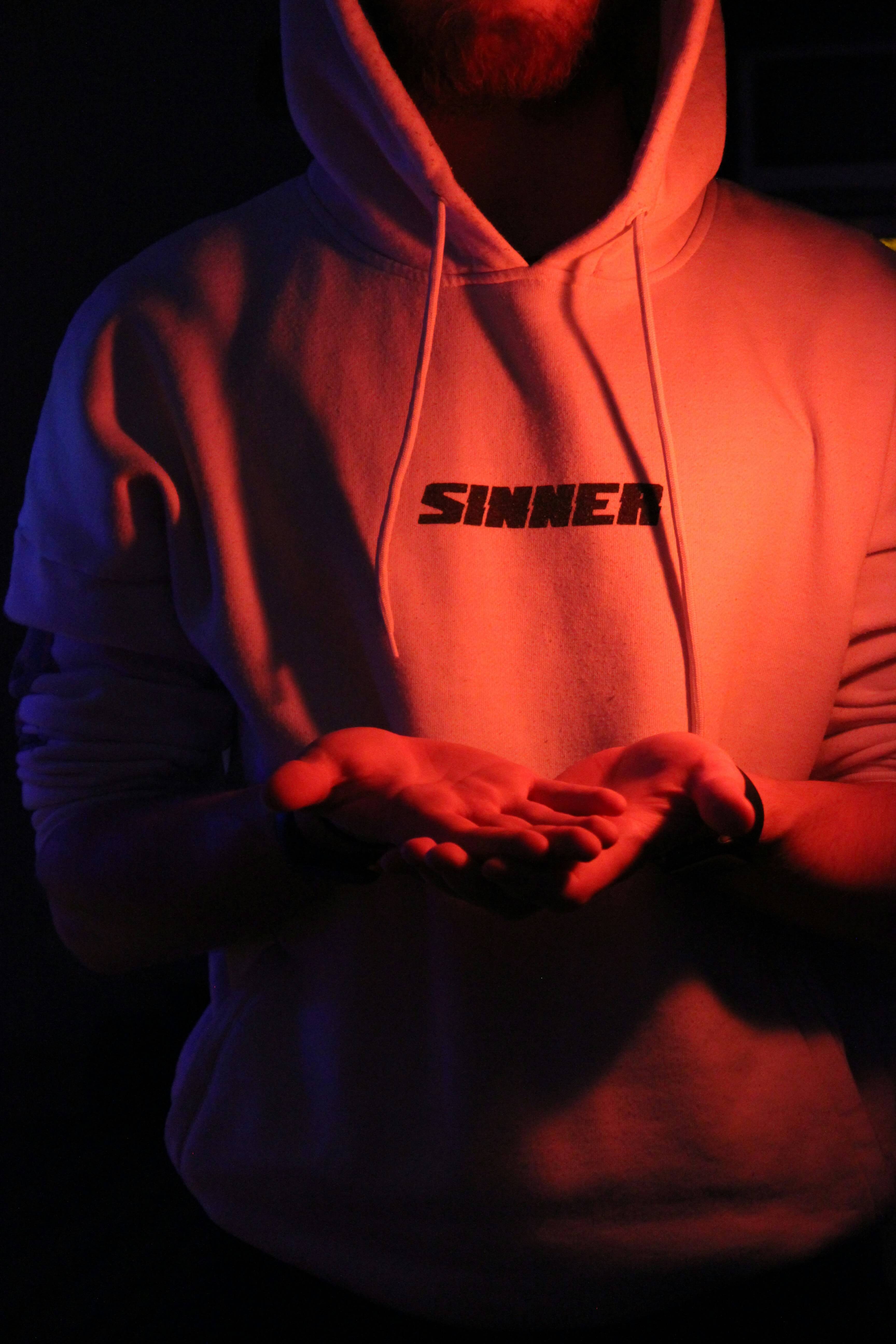 Man wearing hoody with the words sinner